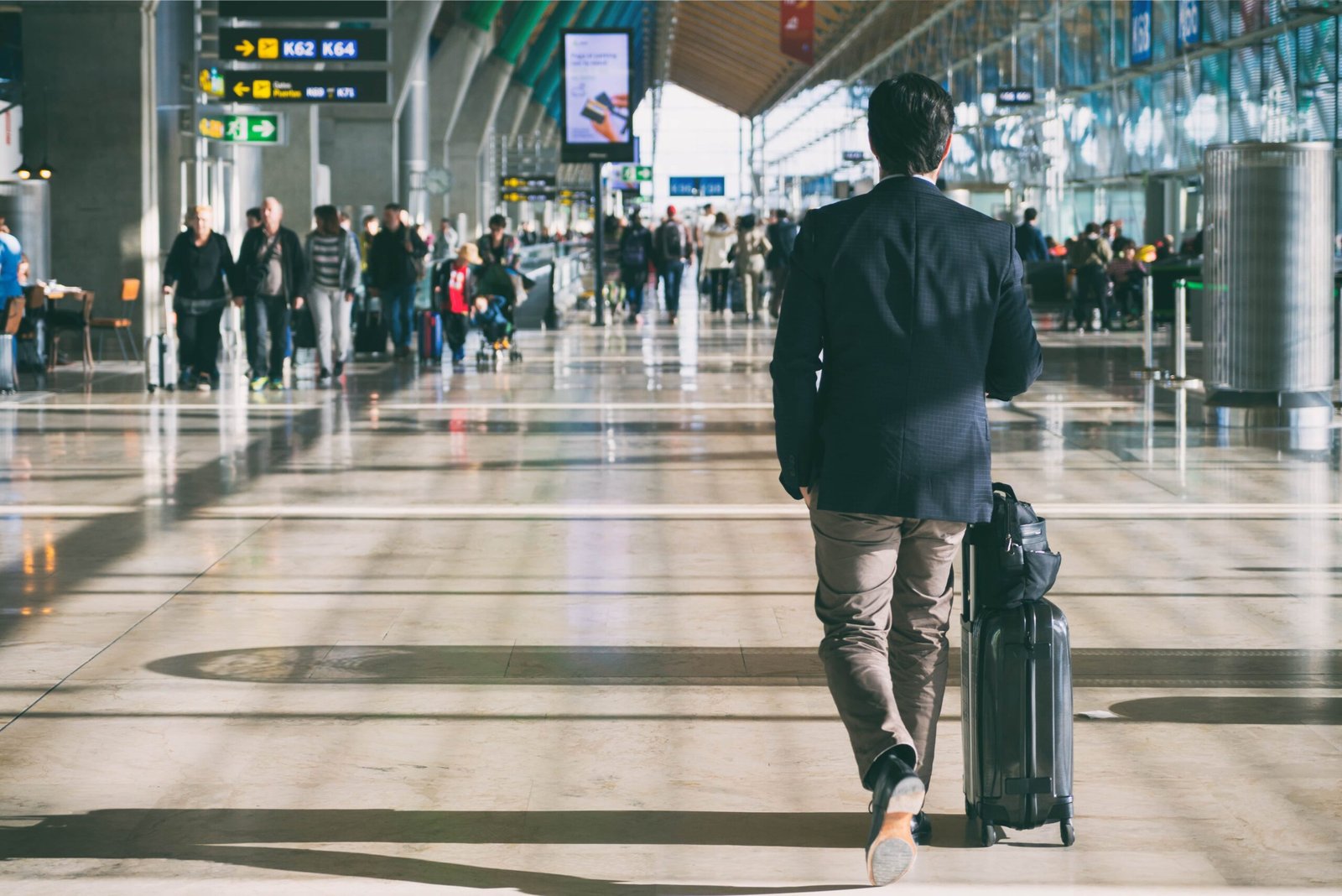 businessman-carrying-suitcase-while-walking-through-passenger-departure-terminal-min
